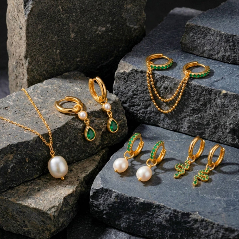 Gold jewelry set with pearls and green gemstones on stone steps