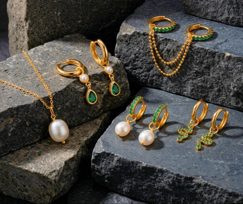 Gold jewelry set with pearls and green gemstones on stone steps