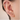 Close-up of an ear with multiple gold and diamond earrings on a neutral background