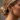 A close-up of a woman's ear adorned with multiple silver-toned hoop and cuff earrings, including one small earring set with light blue-green stones, against a softly blurred neutral background.