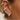 A close-up of a person's ear adorned with multiple silver huggie hoop earrings, including one ear cuff and one small triangular cluster stud, each set with pale blue-green opal-like stones.