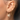 Close-up of an ear with gold earrings and a ring.
